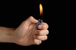 male hand holding a purple lighter with a large flame on a black background