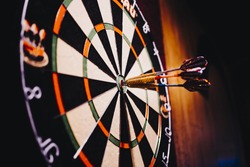Success hitting target aim goal achievement concept background - three darts in bull's eye close up. red three darts arrows in the target center business goal concept
