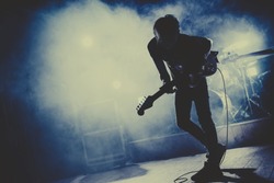 Silhouette of guitar player / guitarist perform on concert stage. Dark background, smoke, concert  spotlights