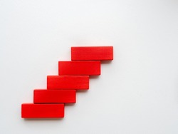 Concept of building success foundation. Women hand put red wooden block in the shape of a staircase