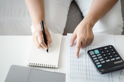 Woman is calculating annual tax with calculator and filling form of Individual Income Tax Return. Season to pay Tax and Budget planning concept. 