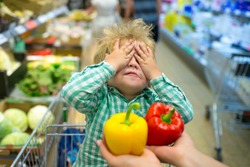 Choice blindly. Hide and seek. Shopping with children. Pepper. Red or yellow pepper. Vegetables in store. Child in shopping cart. No appetite. Vegetable diet. Funny baby dont want eat healthy food