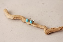 Stud earrings made of natural turquoise sleeping beauty. Designer earrings from natural turquoise stones. Women's jewelry on a light background and wood. Author's modern jewelry.