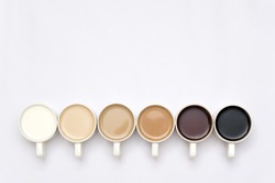 Coffee cups arranged in a creative way creating a gradient colour palette effect on white background