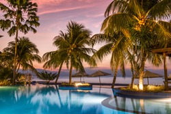 luxury swimmingpool on the beach during sunset with palms and reflections in the water, bali