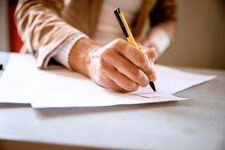 Female hand writing signature on the paper document. Cut out Woman signs agreement or formular contract. Paperwork concept