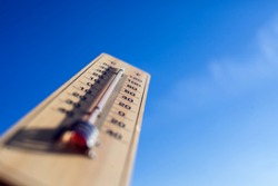 Thermometer on the blue sky background. Weather forecast and outdoor temperature concept
