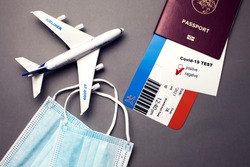 Traveling during COVID-19 pandemic, passport with airline ticket, covid-19 negative test, medical masks and plane on grey background, airport security health and safety check concept