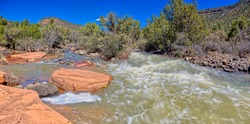 A section of Dry Beaver Creek south of Sedona AZ with red sandstone boulders and rapidly flowing water. Located in Woods Canyon.