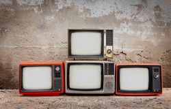 Four retro old television pile on the floor. Four old TVs placed in front of the old cement wall. Antique , Vintage filtered style 
