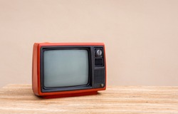 Red old television receiver on wood table with cement wall background. Retro, vintage old TV 