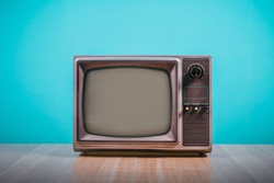 Retro old tv on wooden table with blue concrete wall background.