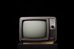 Retro old TV on wooden box on black background
