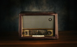 Front view, retro old fashioned radio receiver on wooden table on black background.