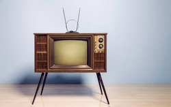 An old retro TV with antenna standing in front of the wall in the room. Antique and vintage television images.