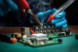 A male technician in gloves is soldering circuit board of CCTV camera. Repairman in workshop
