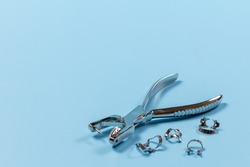 Clamps and the dental hole punch on the blue background. Medical tools concept. Top view.