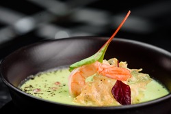 Green Cream Soup with Shrimp . Thai food Shrimp green curry in a dark plate on a black background. close up. space