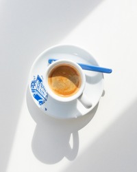 Espresso in a white cup with a blue print in the morning with shadows from the window