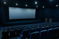 Empty blue cinema room with white screen and seats. Side view
