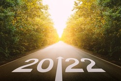 The new year 2022 or straightforward concept. Text 2022 written on the road in the middle of asphalt road at sunset. planning and challenge, business strategy, opportunity, hope, and new life.
