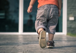 close up of child legs walking away from camera toward house door