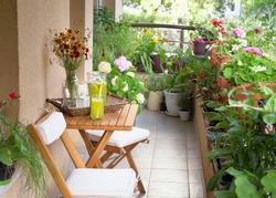 Beautiful terrace or balcony with small table, chair and flowers. Summer time Idyllic seating in the terrace with drink.