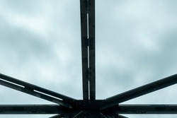 Part of the steel spans of a bridge etched against a cloudy sky