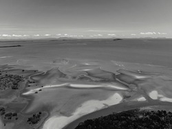 Aerial landscape pattern of ocean sands at low tide towards horizon, rendered in monotone