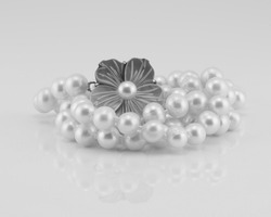 A string of lustrously glowing pearls designed as a necklace with a flower clasp, isolated on a white background