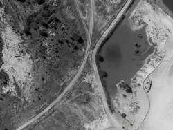 Drone aerial over ponds of water and dirt tracks caused by sapphire miners in central Queensland, Australia. Monotone image.
