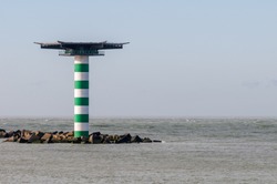 The striped lighthouse Maasmond with heliplatform at the entrance of the Port of Rotterdam in the Netherlands. The lighthouse is situated at the end of pier Zuiderdam with concrete wave breakers.