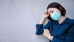 Healthy woman in green medical protective mask showing gesture stop. Health protection and prevention during flu and infectious outbreak or Covid-19 at congrete wall 