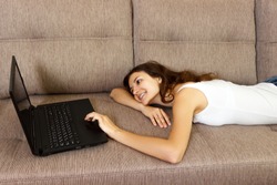 smiling woman with laptop looking to side at home.