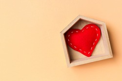 Top view of red textile heart in a wooden house on colorful background. Home sweet home concept. Valentine's day.