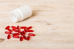 Red pills spilled around a pill bottle. Medicines and prescription pills flat lay background. Red medical capsules.