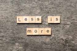 less is more word written on wood block. less is more text on table, concept.