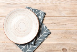 Top view on colored background empty round white plate on tablecloth for food. Empty dish on napkin with space for your design.