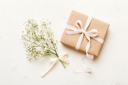 Gift or present box and flower gypsophila on light table top view. Greeting card. Flat lay style with copy space.