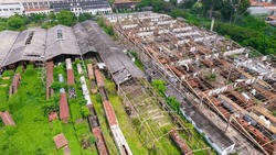 abandoned train station and wagon, with forest covering part of them. Aerial view on the city of Sorocaba, Brazil.