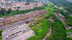abandoned train station and wagon, with forest covering part of them. Aerial view on the city of Sorocaba, Brazil.