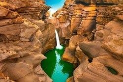 waterfall landscape in nature. Spectacular nature view with the waterfall pouring through the huge rocks. Waterfall view in red canyon. Nature landscape in the mountain. 