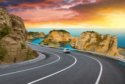 highway landscape at colorful sunset. road view on mediterranean coast of spain. coastal road landscape beautiful nature scenery. car driving on mountain road by the sea. summer vacation on the beach.
