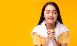 Christian young lady praying to God. Woman praying with hands together on yellow background. Attractive girl thank you for god blessing to wishing have a better life. She believe in goodness, hopeful