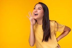Surprised happy beauty asian woman looking copy space in excitement. Expressive facial expressions. Presenting some product. Beautiful girl act like a telling someone Isolated on yellow background
