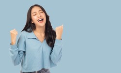 Excited young asian female with raised hands celebrating success Portrait cheerful positive asian woman with raised hands and fists open mouth Girl get happy, enjoy life isolated on blue copy space