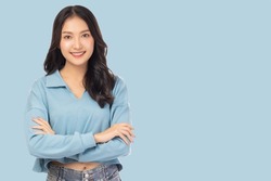 Portrait smiling young asian woman with crossed arms Happy asia girl posing with crossed arms and looking at camera over light blue background and copy space Confident female get happy and feel relax