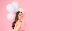 Happy asian woman holding balloons looking at camera in excitement Expressive facial expressions Beautiful girl enjoy holiday and celebrate for party or special day Use for advertising Pink background