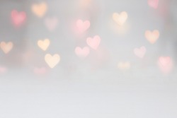 Valentine background mockup with pink and yellow heart shaped light bokeh on a grey seamless backdrop. Use for digital product mockup placement or as a background for text.