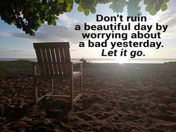 Inspirational motivational quote - Don't ruin a beautiful day by worrying about a bad yesterday. Let it go. With empty chair under the shady tree on the beach against bright sky sunlight over horizon.